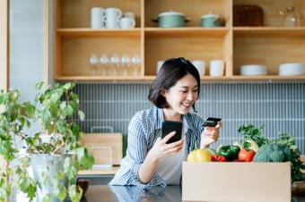 Woman making an online payment in a kitchen